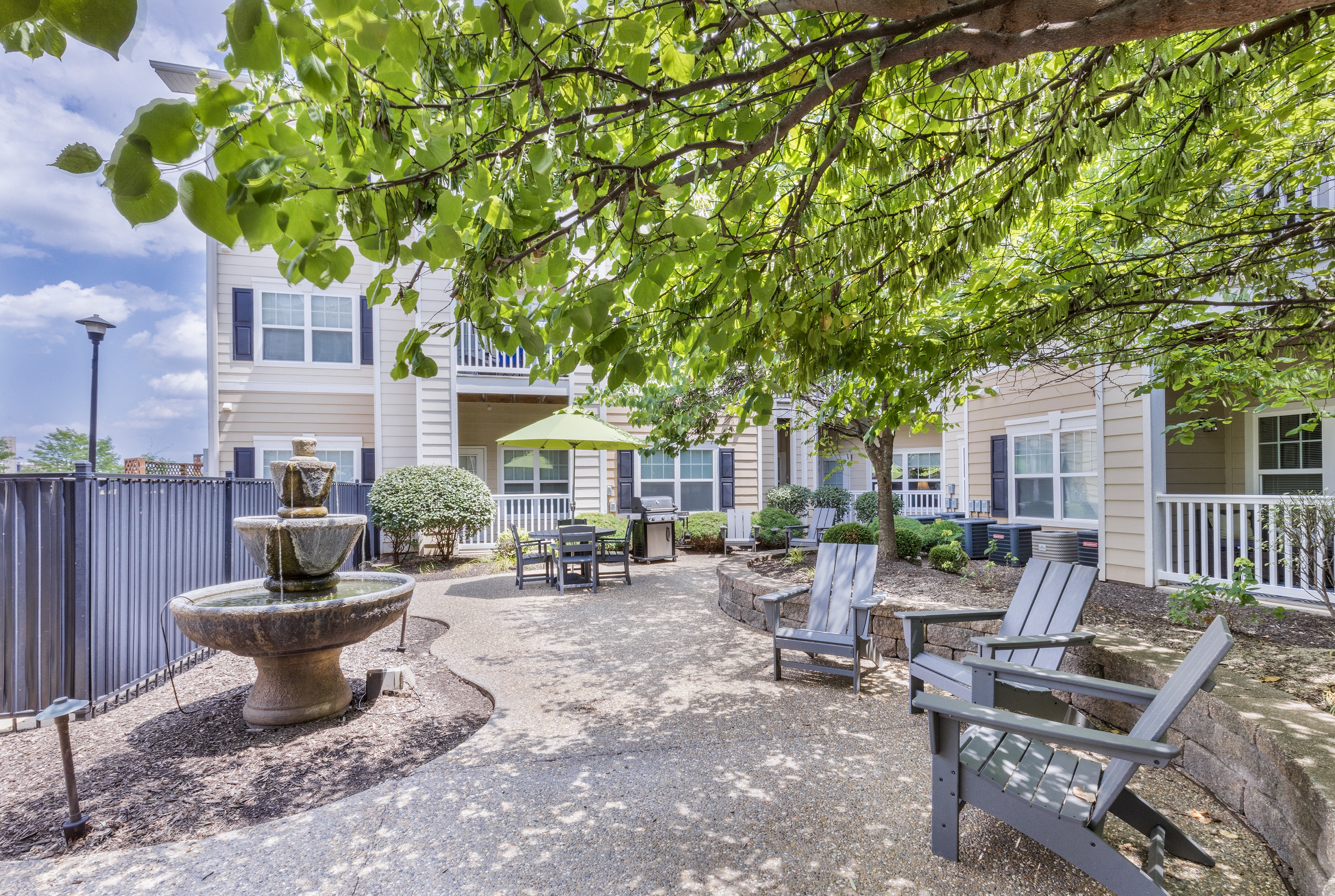 a courtyard with a fountain and benches in front of a building at Aventura at Forest Park, St. Louis